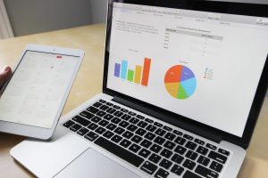 Ordenador portátil con gráficos y I pad reflejando un calendario